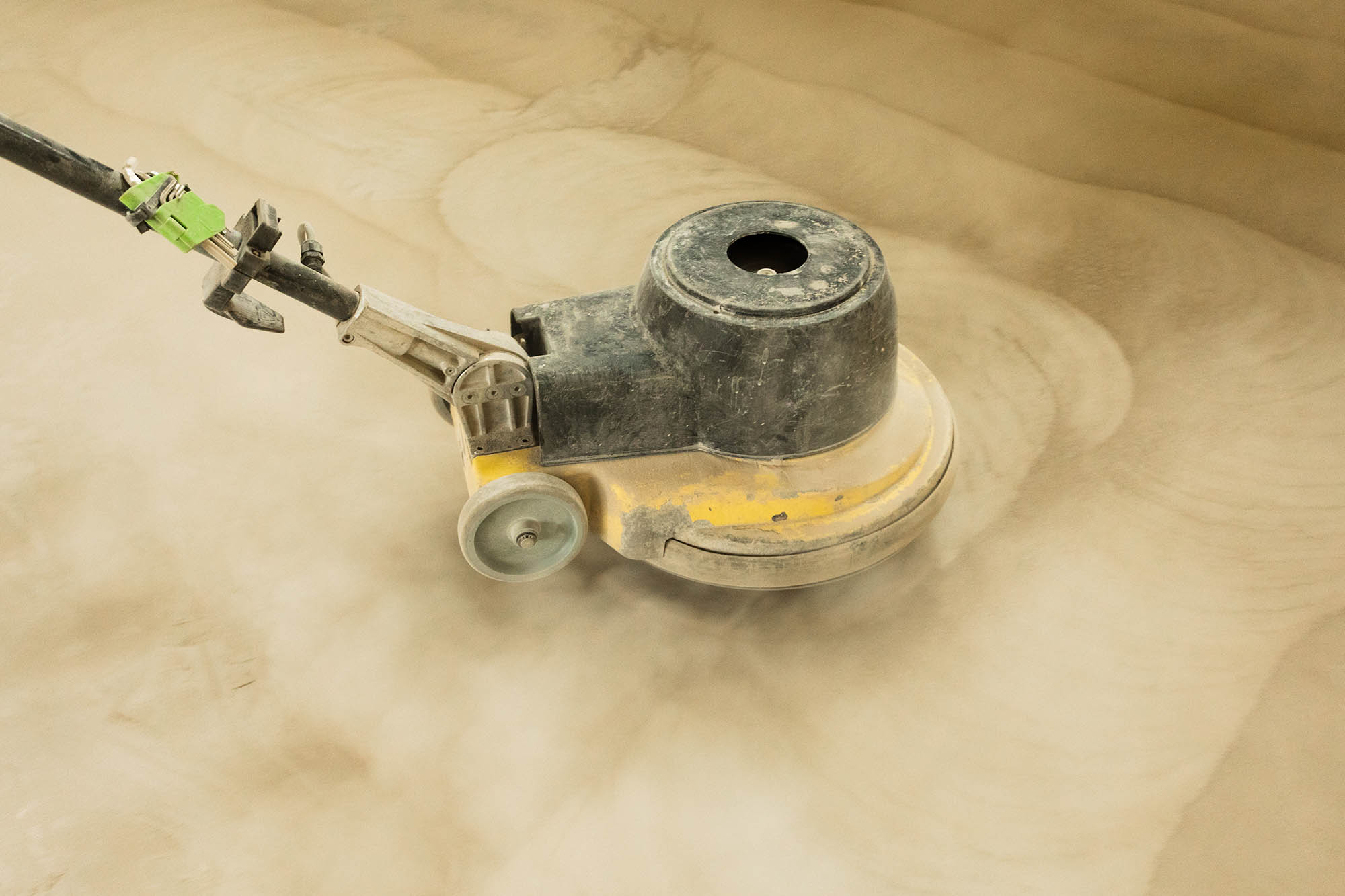 A,man,builder,grinds,a,concrete,floor,with,a,sander